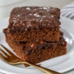 Two slices of chocolate cake on a white plate.