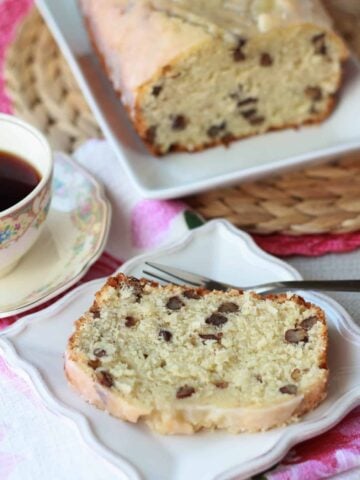 Slice of cake on a white plate with a cup of coffee.