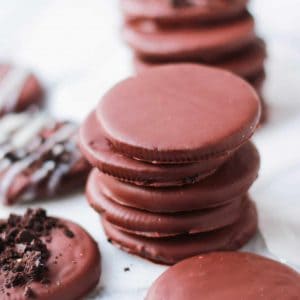 Stack of thin chocolate cookies on a white board.