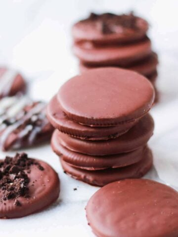 Stack of thin chocolate cookies on a white board.