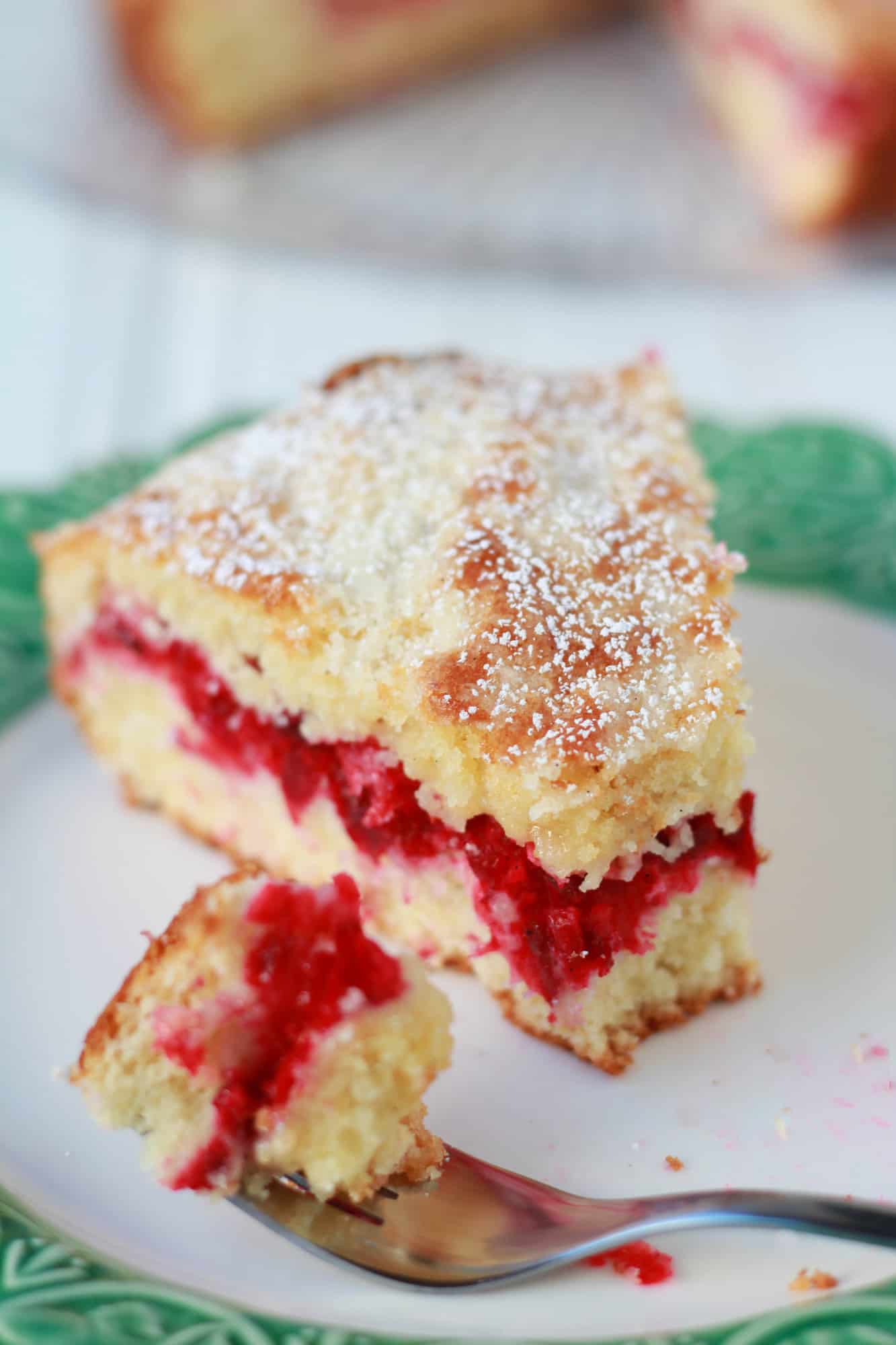 Slice of cranberry cake on a green and white plate.