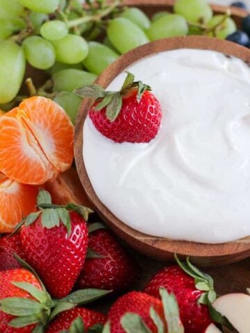 Bowl of dip with fruit around it.