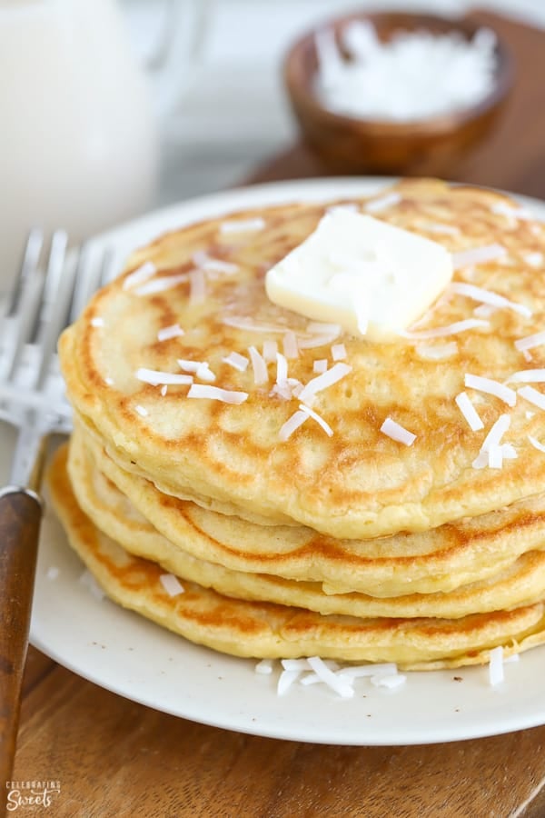 A stack of coconut pancakes topped with butter and shredded coconut.