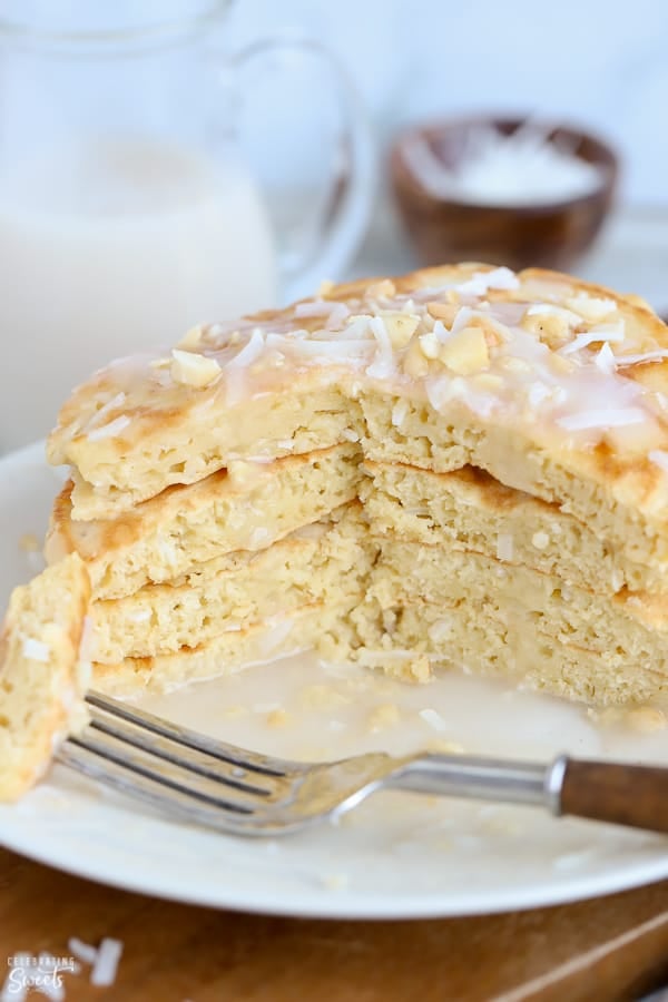 Stack of coconut pancakes on a white plate with a fork.