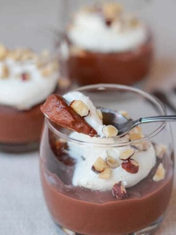 Glass filled with pudding and whipped cream and garnished with nuts.