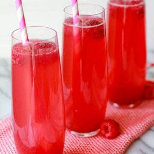 Three thin glasses filled with a pink beverage.