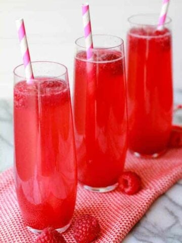 Three thin glasses filled with a pink beverage.
