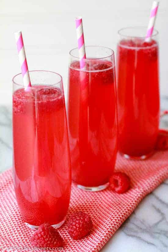 Three thin glasses filled with a pink beverage.