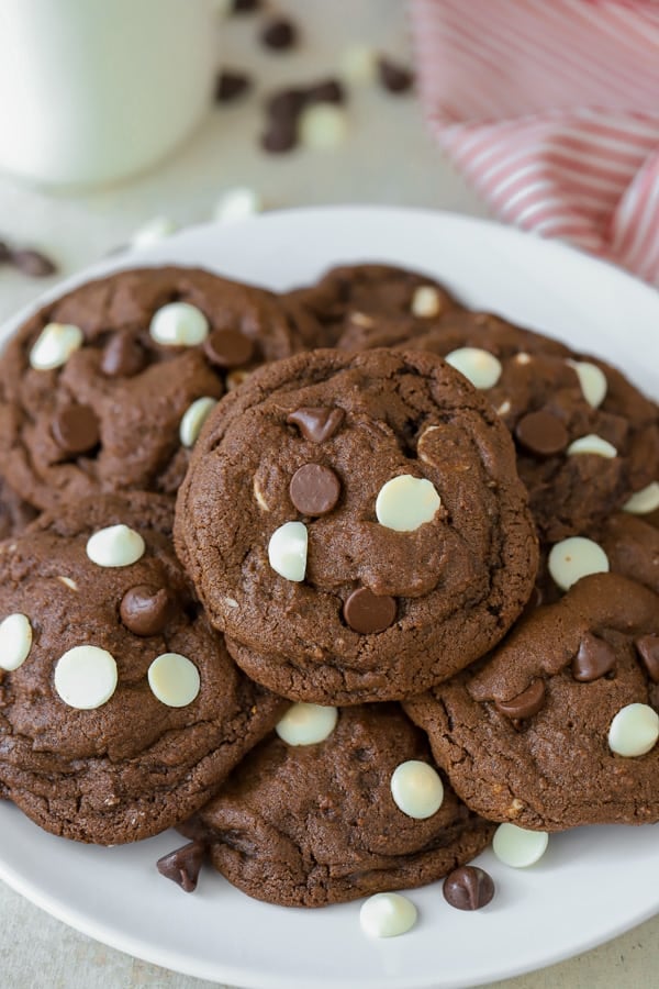 White plate filled with chocolate cookies filled with white chocolate chips.