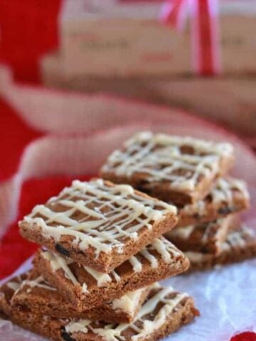 Stacks of gingerbread bars drizzled with icing on a piece of parchment paper.
