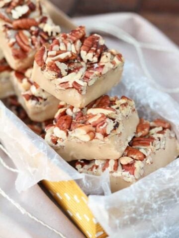 White chocolate fudge topped with pecans in a yellow box.