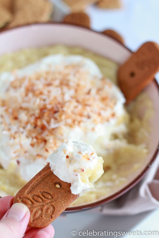 Bowl of coconut pie dip topped with whipped cream, toasted coconut and cookies.