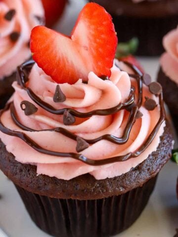 Chocolate cupcake topped with strawberry frosting and a heart shaped strawberry.