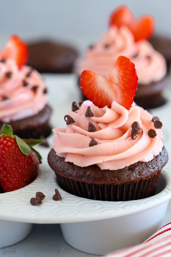 Chocolate cupcake topped with strawberry frosting and a heart shaped strawberry.