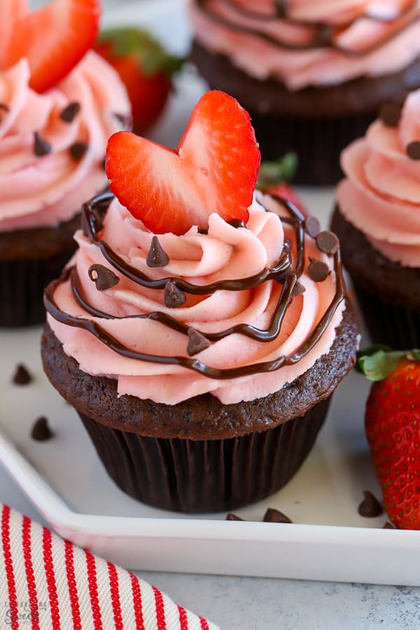 Chocolate cupcake topped with strawberry frosting and a heart shaped strawberry.