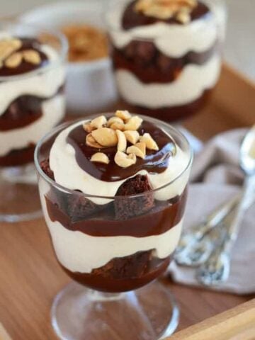Glass trifle dish with layers of brownies, whipped cream, and fudge.