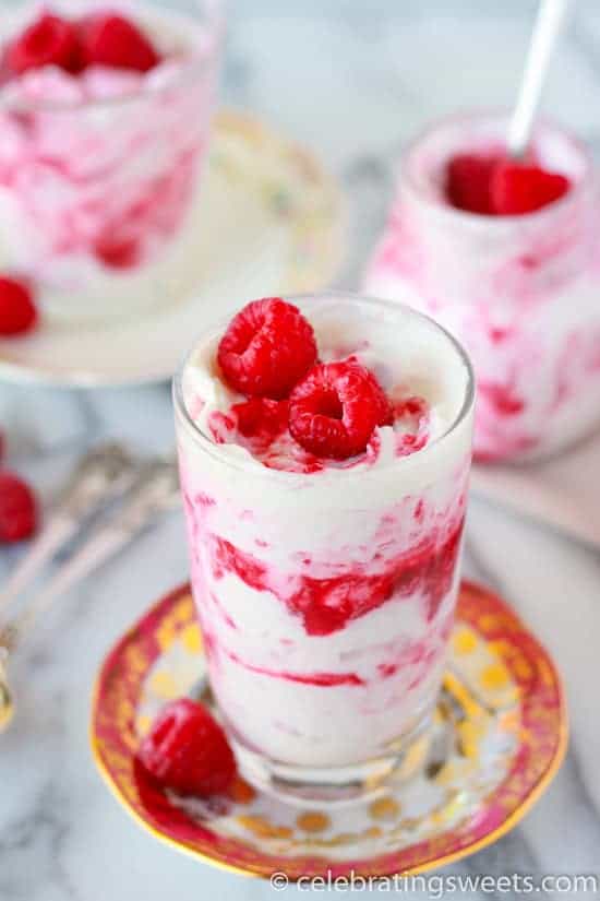 Glass filled with layers of whipped cream and raspberries.