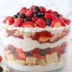 Large trifle dish with layers of berries, cake and whipped cream.