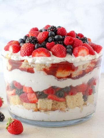 Large trifle dish with layers of berries, cake and whipped cream.