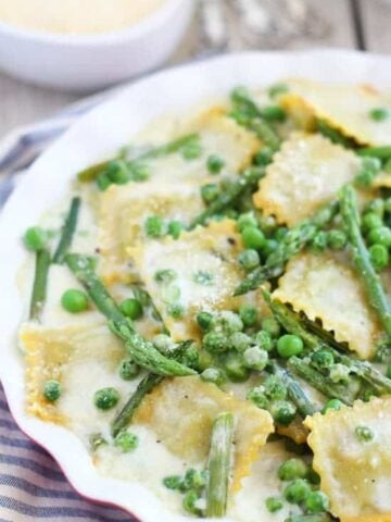 Ravioli with peas and asparagus in a baking dish.