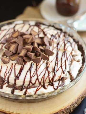 A close up of a peanut butter ice cream pie topped with fudge sauce.