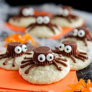 Sugar cookies decorated to look like a spider on an orange napkin.