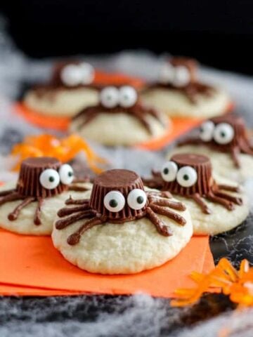 Sugar cookies decorated to look like a spider on an orange napkin.