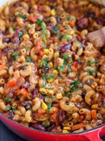 Chili mac in a skillet with a wooden spoon.