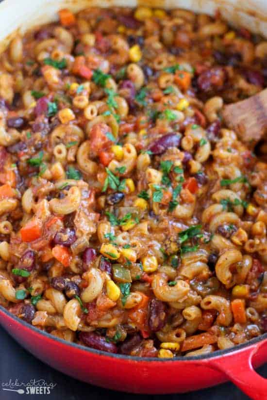 Chili mac in a skillet with a wooden spoon.