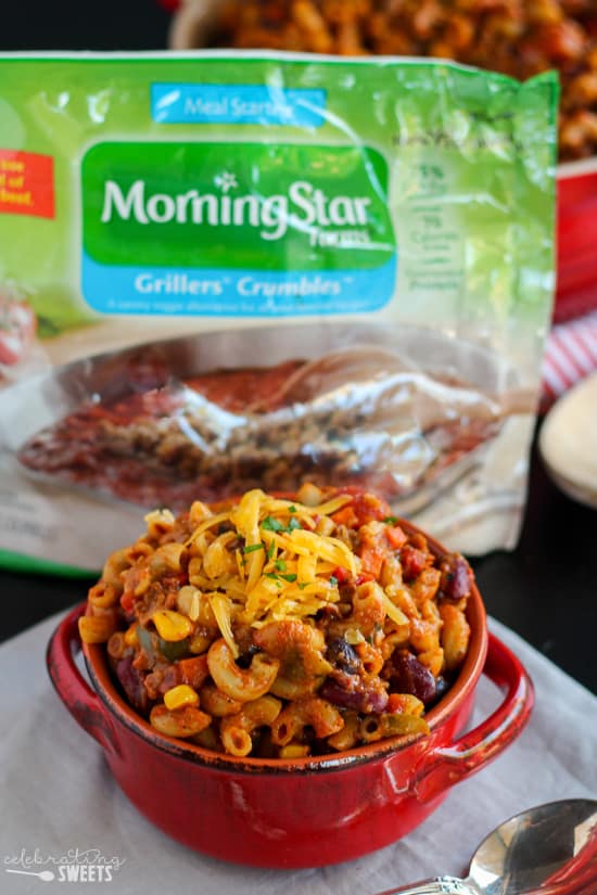 Chili mac in a red bowl topped with cheese.