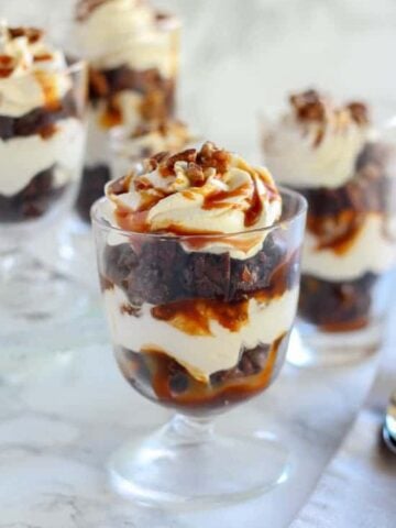 Brownie trifles in a glass dish topped with caramel.
