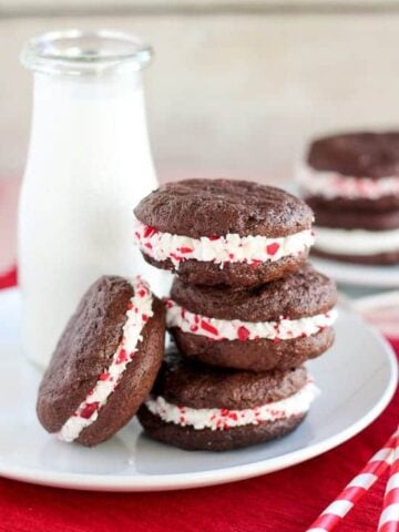 Stack of peppermint sandwich cookies with milk in the background.