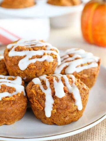 Healthy Pumpkin Muffins ona white plate with a pumpkin in the background.