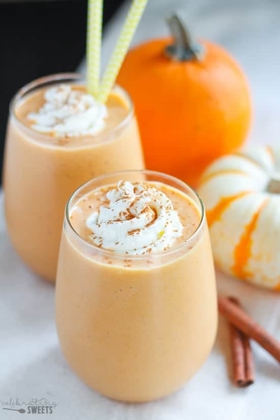Pumpkin smoothie in a glass topped with whipped cream and cinnamon.