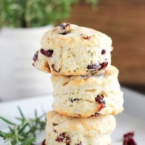 Stack of three cranberry muffins on a white plate.