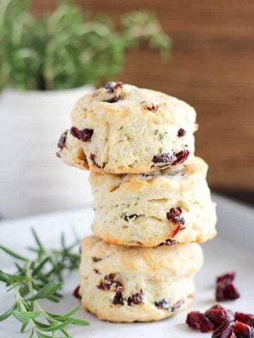 Stack of three cranberry muffins on a white plate.