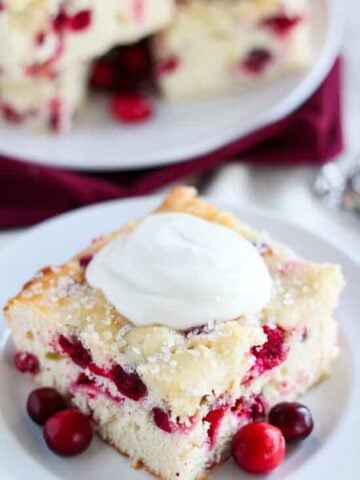 Cranberry cake on a white plate topped with yogurt.