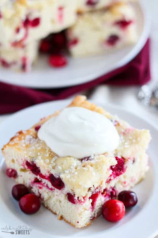 Cranberry cake on a white plate topped with yogurt.