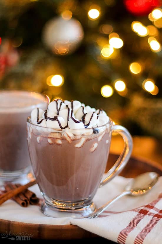 Glass of hot chocolate topped with marshmallows and a drizzle of chocolate sauce.