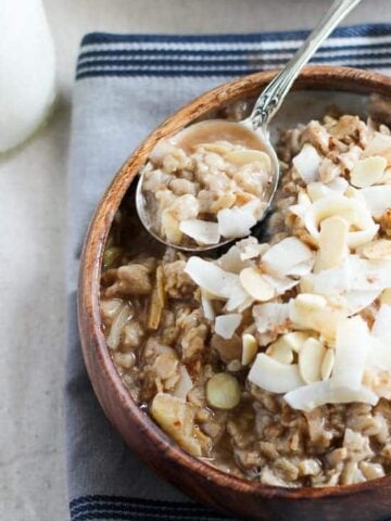 Bowl of oatmeal topped with coconut and almonds.