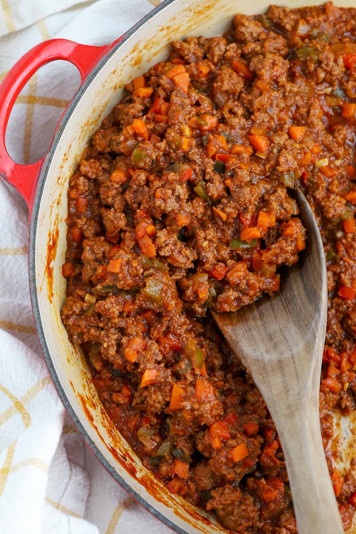 Sloppy joe meat in a pan with a wooden spoon