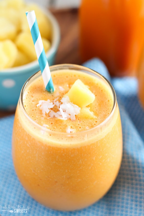 Carrot smoothie in a glass with a turquoise napkin underneath.