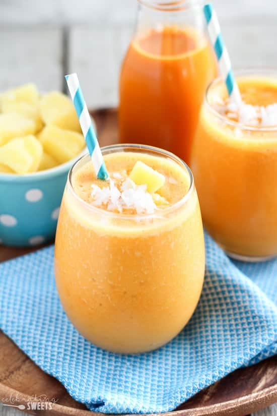 Carrot smoothie in a glass with a turquoise napkin underneath.