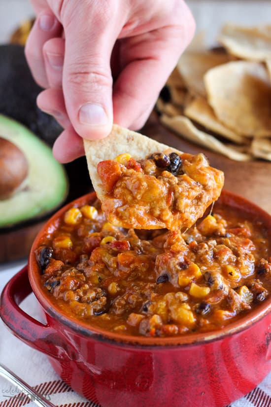 Taco soup in a red bowl with tortilla chips.