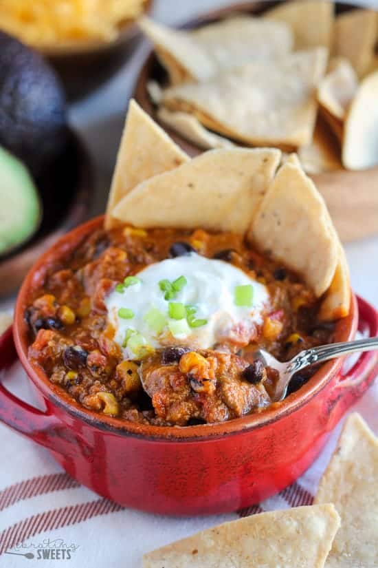 Taco soup in a red bowl with chips and sour cream.
