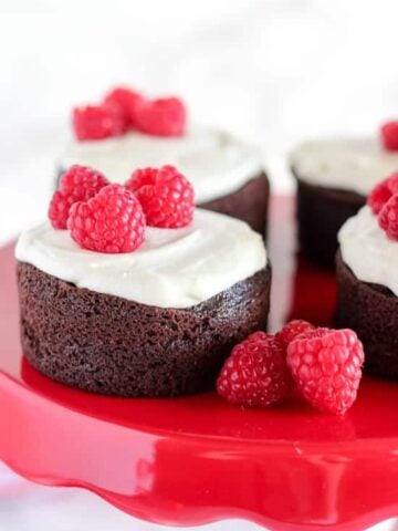 Small round cake topped with frosting and raspberries.