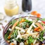 A bowl of salad with apples and dried fruit.