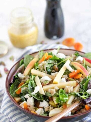 A bowl of salad with apples and dried fruit.