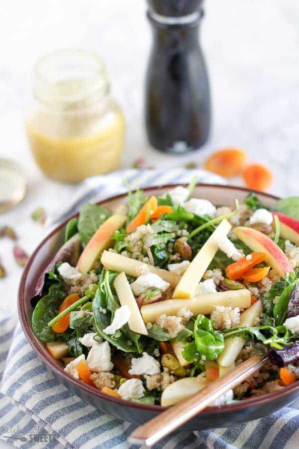 A bowl of salad with apples and dried fruit.