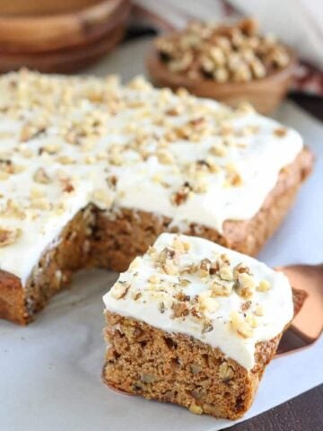 Square slice of carrot cake topped with white frosting.